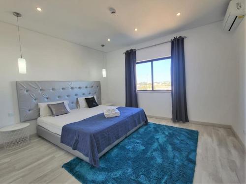 Un dormitorio con una cama grande y una alfombra azul en AL Sunset, en Albufeira