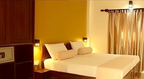 1 dormitorio con cama blanca y ventana en Inlak Garden Hotel en Negombo