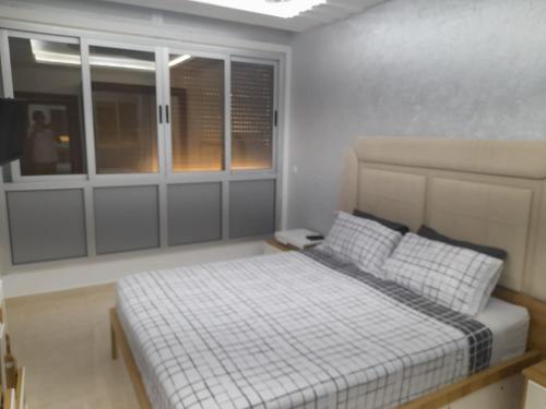 a bedroom with a bed in a room with windows at appartement mdiq tetouan, 2 chambres 1 double salon in M'diq
