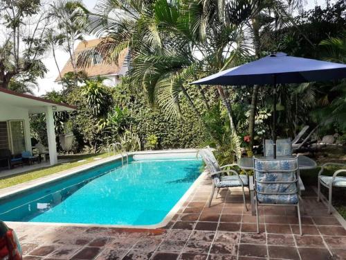 - une piscine avec un parasol, une table et des chaises dans l'établissement Brisas Verdes. Increíble espacio con alberca climatizada, à Temixco