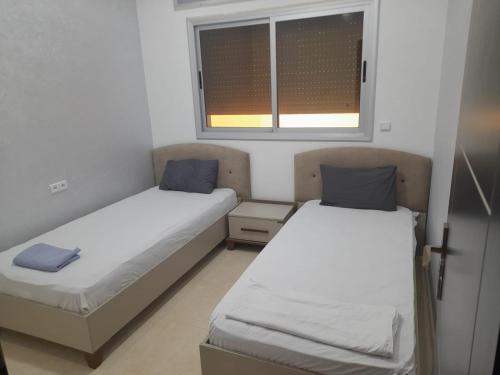 two beds in a small room with a window at appartement mdiq tetouan, 2 chambres 1 double salon in M'diq
