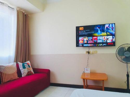 Cette chambre dispose d'un canapé et d'une télévision murale. dans l'établissement BAGUIO CONDO ALBERGO HOTEL by DEI GRATIA, à Baguio