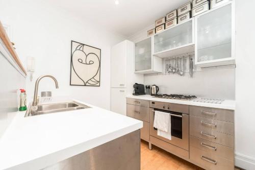 una cocina con encimeras blancas y electrodomésticos de acero inoxidable en Chic Top Floor Apartment in the heart of Notting Hill Ladbroke Grove en Londres