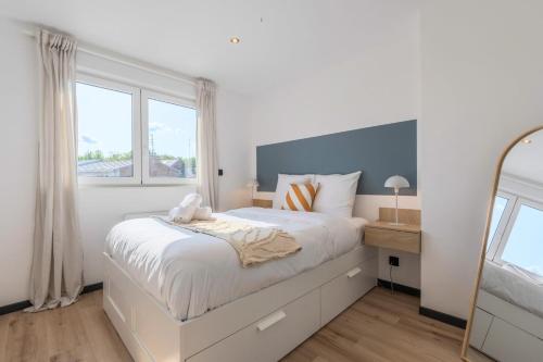 a white bedroom with a large bed and a mirror at House 4bed 2bath with garden and private parking. in La Madeleine
