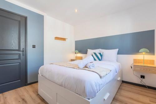 a bedroom with a large white bed with blue walls at House 4bed 2bath with garden and private parking. in La Madeleine