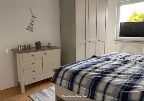 a bedroom with a bed and a dresser and a window at Haus Roter Sand in Hooksiel in Wangerland