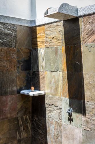 a shower with a stone wall in a bathroom at Mantra Koodam Kumbakonam - A CGH Earth Experience in Kumbakonam