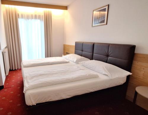 a bed in a hotel room with a large window at Hotel Hubertushof in Vipiteno