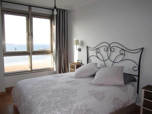 een slaapkamer met een groot bed en een groot raam bij Sunshine beach Gijón in Gijón