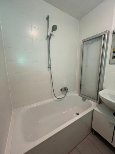 a white bathroom with a tub and a sink at Mini Loft Apartment in Garmisch-Partenkirchen