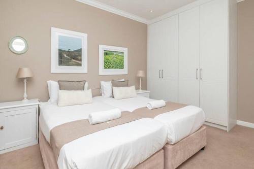 una camera con due grandi letti con lenzuola bianche di 2 Bedroom Apartment With Amazing City Views a Città del Capo