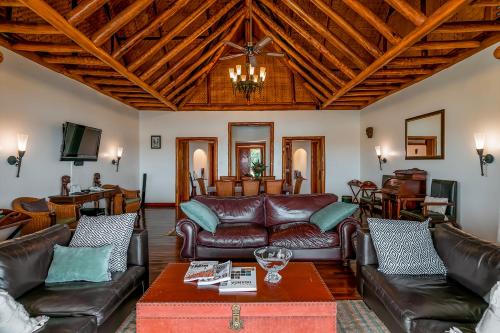 a living room with leather furniture and a wooden ceiling at Mweya Safari Lodge in Katwe