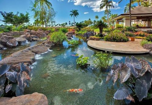 a pond in a garden with a waterfall and rocks at Ko Olina Beach Villas O704 in Kapolei