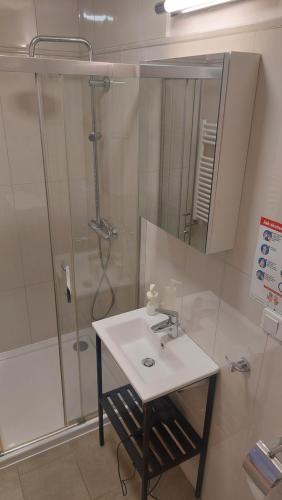 uma casa de banho com um lavatório e um chuveiro com um espelho. em Kazimierz Center Apartments Halicka em Cracóvia
