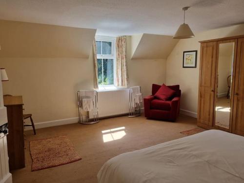 1 dormitorio con 1 cama y 1 silla roja en The Coach House - Bargany en Girvan