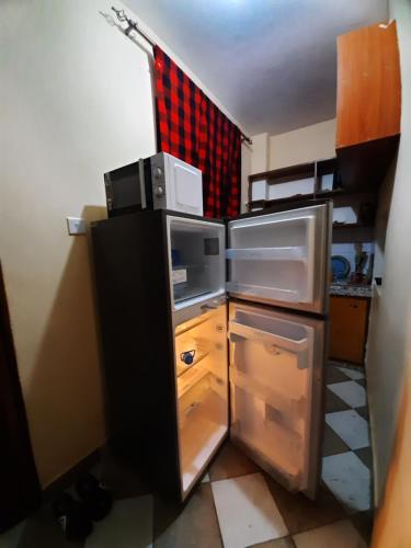 małą kuchnię z lodówką z otwartymi drzwiami w obiekcie Kilifi Homes apt E-5 w mieście Kilifi