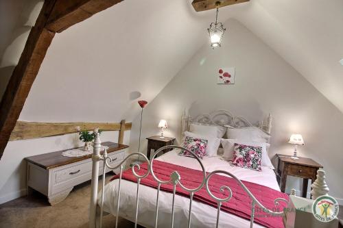 una camera da letto con un letto bianco con lenzuola e cuscini rosa di Le parfum des fleurs a Plussulien