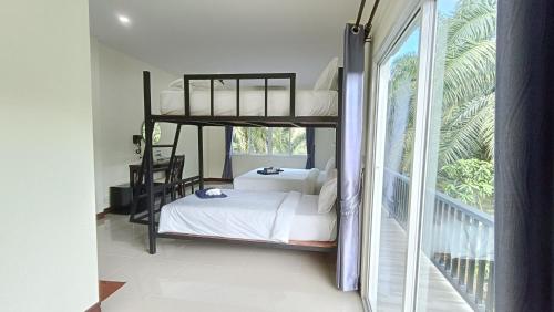 a bedroom with two bunk beds and a balcony at Khao Sok Family Room House in Khao Sok National Park