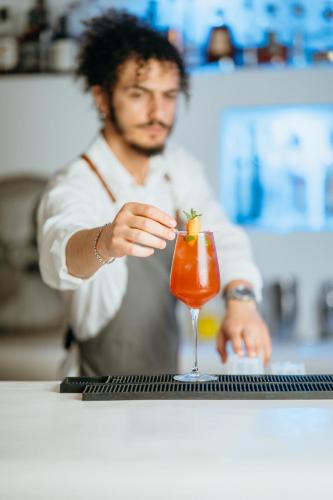 a man standing at a bar stirring a cocktail at DeLight Boutique Hotel - Small Luxury Hotels of the World in Agios Ioannis Mykonos