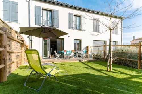 une chaise verte et un parasol dans la cour d'une maison dans l'établissement Villa Paulina, cœur village, à 5 min de la plage, à Portiragnes