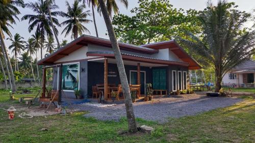 a small house with a palm tree in front of it at บ้านระเบียงเลหลังสวน 1 ห้อง in Ban Hin Sam Kon