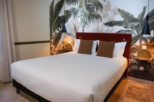 坎城的住宿－戛納中心普魯伊別墅酒店，卧室配有白色的床铺,墙上挂着植物
