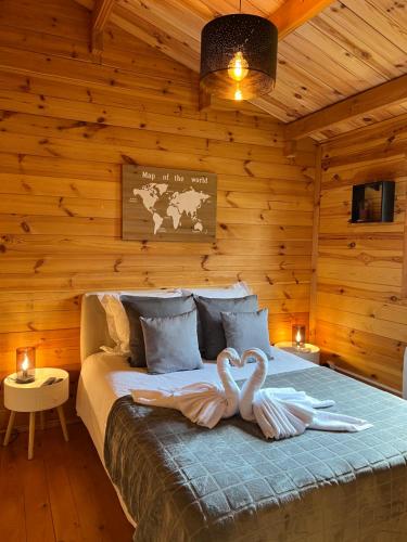Deux cygnes sont assis sur un lit dans une cabine dans l'établissement L'Enseigne -Location de 2 chalets privatifs avec Spa, à Venizel