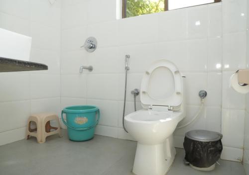 a bathroom with a toilet and a trash can at Falling Water Resort By Travent Mug in Sakleshpur