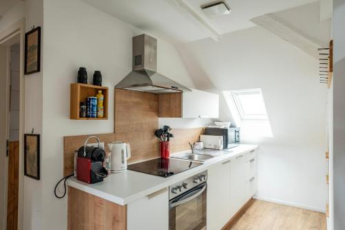 une cuisine avec des armoires blanches et un évier dans l'établissement Le Schoepflin - Coeur de Strasbourg - Vue toits, à Strasbourg