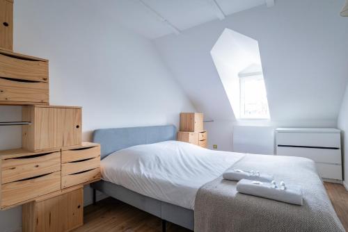 une chambre avec un lit, une commode et une fenêtre dans l'établissement Le Schoepflin - Coeur de Strasbourg - Vue toits, à Strasbourg