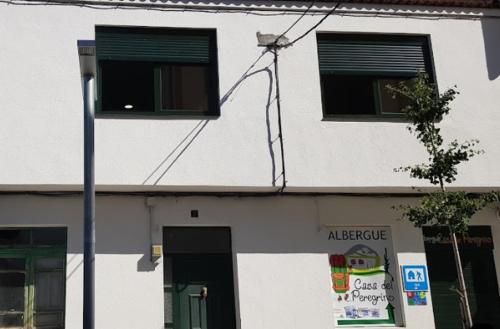 un edificio blanco con 2 ventanas y luz de la calle en Casa del Peregrino, en Arzúa