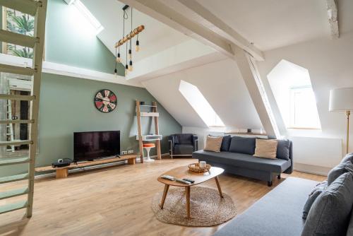 un salon avec un canapé et une télévision dans l'établissement Le Schoepflin - Coeur de Strasbourg - Vue toits, à Strasbourg