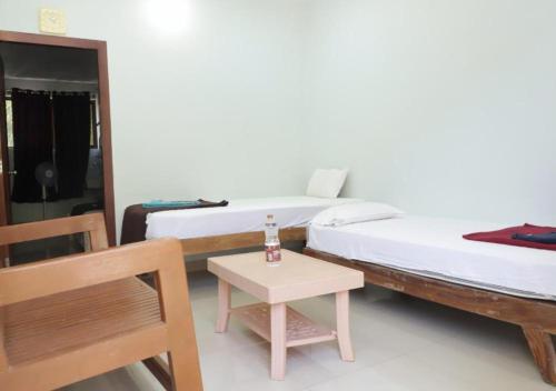 a room with two beds and a table and a chair at Falling Water Resort By Travent Mug in Sakleshpur