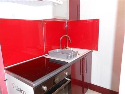 uma cozinha vermelha com um lavatório e uma parede vermelha em Appartement Saint-Hilaire-de-Riez, 3 pièces, 6 personnes - FR-1-324A-21 em Saint-Hilaire-de-Riez