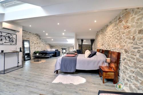 une chambre avec un lit et un mur en pierre dans l'établissement La bastide Maë, à Saint-Remèze