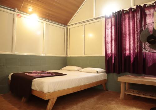 a bedroom with a bed with purple curtains at Falling Water Resort By Travent Mug in Sakleshpur
