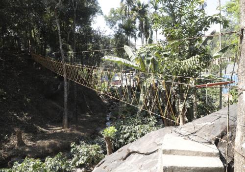a rope bridge in the middle of a forest at Falling Water Resort By Travent Mug in Sakleshpur
