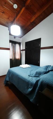 a bedroom with a bed with a blue comforter at HOSPEDAJE EL GRINGO - CASA ALOJAMIENTO COMPLETO in Río Grande