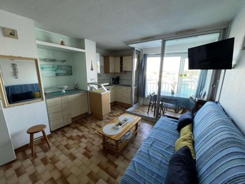 un salon avec un canapé bleu et une cuisine dans l'établissement Studio Cabine avec Ascenseur, Parking Privé, Animaux Acceptés, Plage à Proximité - FR-1-702-28, au Cap d'Agde