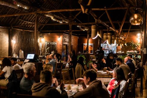 a group of people sitting at tables in a restaurant at Oxygen Paje Hotel in Paje