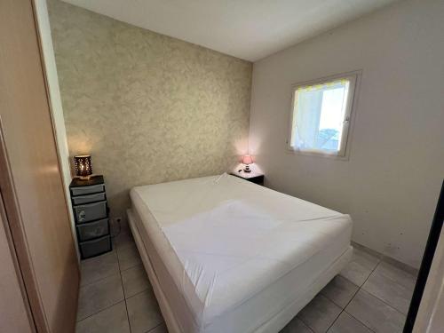 um quarto com uma cama branca e uma janela em Appartement Valras-Plage, 2 pièces, 3 personnes - FR-1-701-67 em Valras-Plage