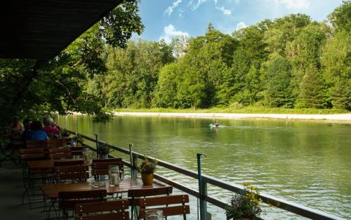 a restaurant with tables and chairs next to a river at Oktoberfest on a Budget Munich in Munich