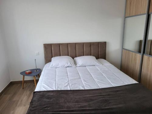 Cette chambre comprend un lit avec des draps blancs et une table. dans l'établissement Villa pieds dans l'eau, 4 pers, 2 chambres, terrasse, parking, plage directe, Grau d'Agde - FR-1-749-39, au Grau-dʼAgde