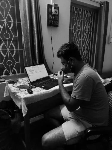 a man sitting at a desk with a laptop computer at Roadji Stays 001, Madhuri Villa in Agartala