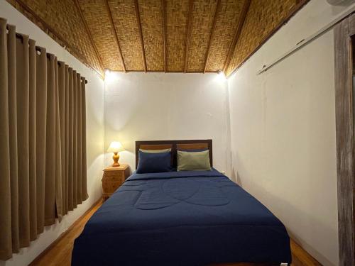 a bedroom with a bed with a blue comforter at Rumah Tiga Gili in Gili Air