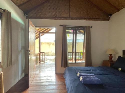 a bedroom with a blue bed and a balcony at Rumah Tiga Gili in Gili Air