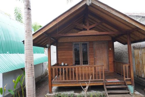 a small wooden house with a porch at Rumah Tiga Gili in Gili Air
