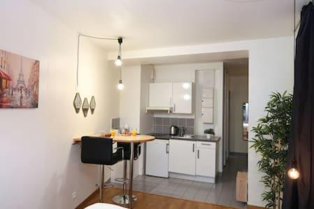 une cuisine avec des armoires blanches et une table à l'intérieur dans l'établissement 101 - Studio confortable avec kitchenette Paris 5 - FLAT-GUEST, à Paris