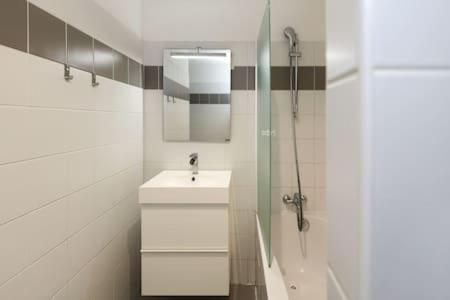 une salle de bain blanche avec un lavabo et une douche dans l'établissement 101 - Studio confortable avec kitchenette Paris 5 - FLAT-GUEST, à Paris