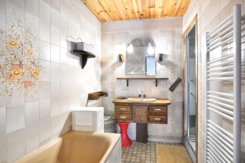 une salle de bain avec une baignoire, un lavabo et un miroir dans l'établissement La Chaumière - Maison à moins d’un km de la plage, à Saint-Jean-de-la-Rivière